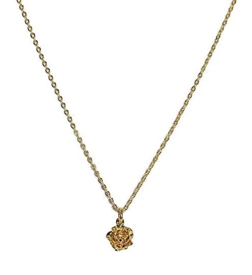 A gold chain necklace with a flower pendant made by Meghan Bo Designs lays on a flat white surface.